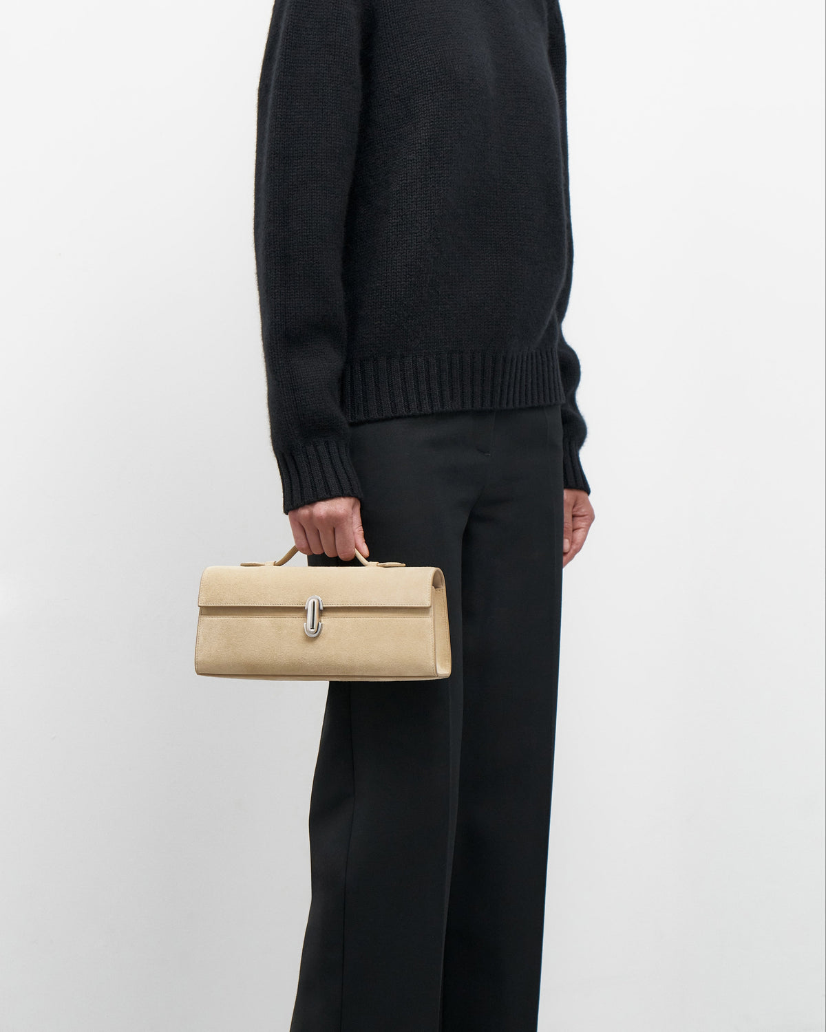 Person holding a beige handbag against a plain background