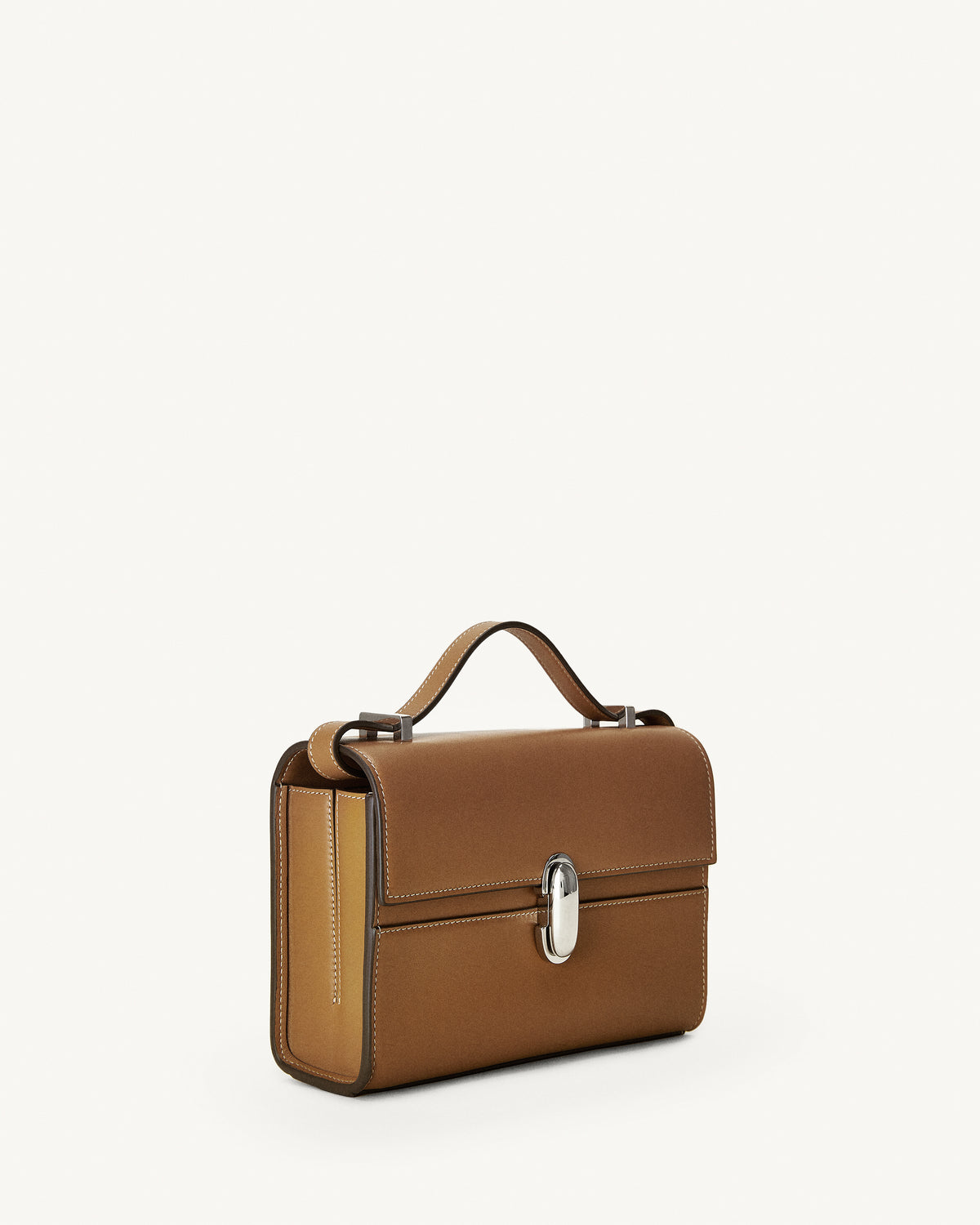 side view of a saddle brown leather bag with a silver clasp on a white background