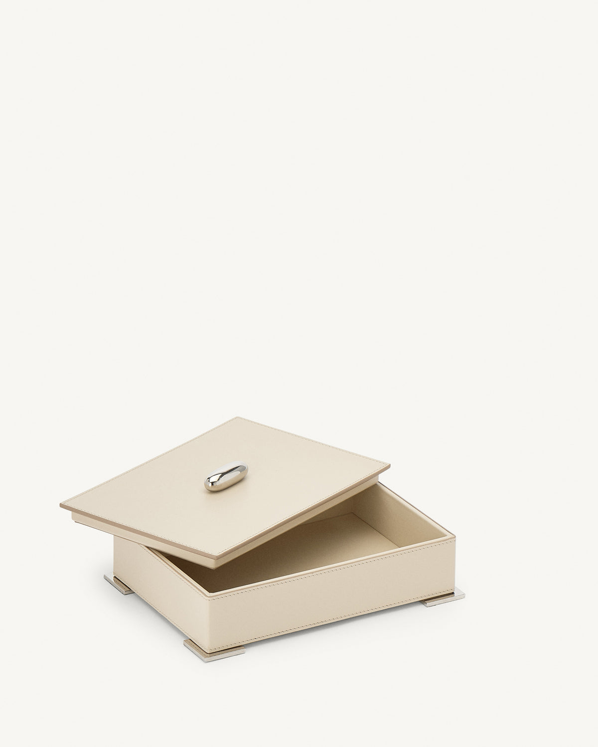 interior view of a parchment beige leather box with silver metal hardware on a white background
