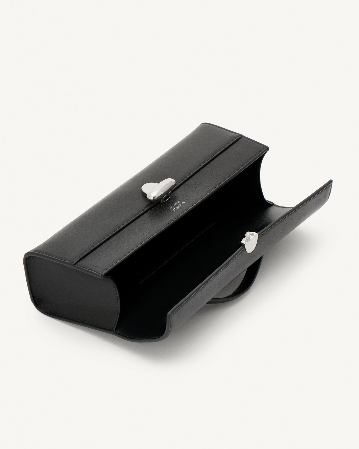 interior view of vintage black leather top handle bag with matte silver clasp on a white background 
