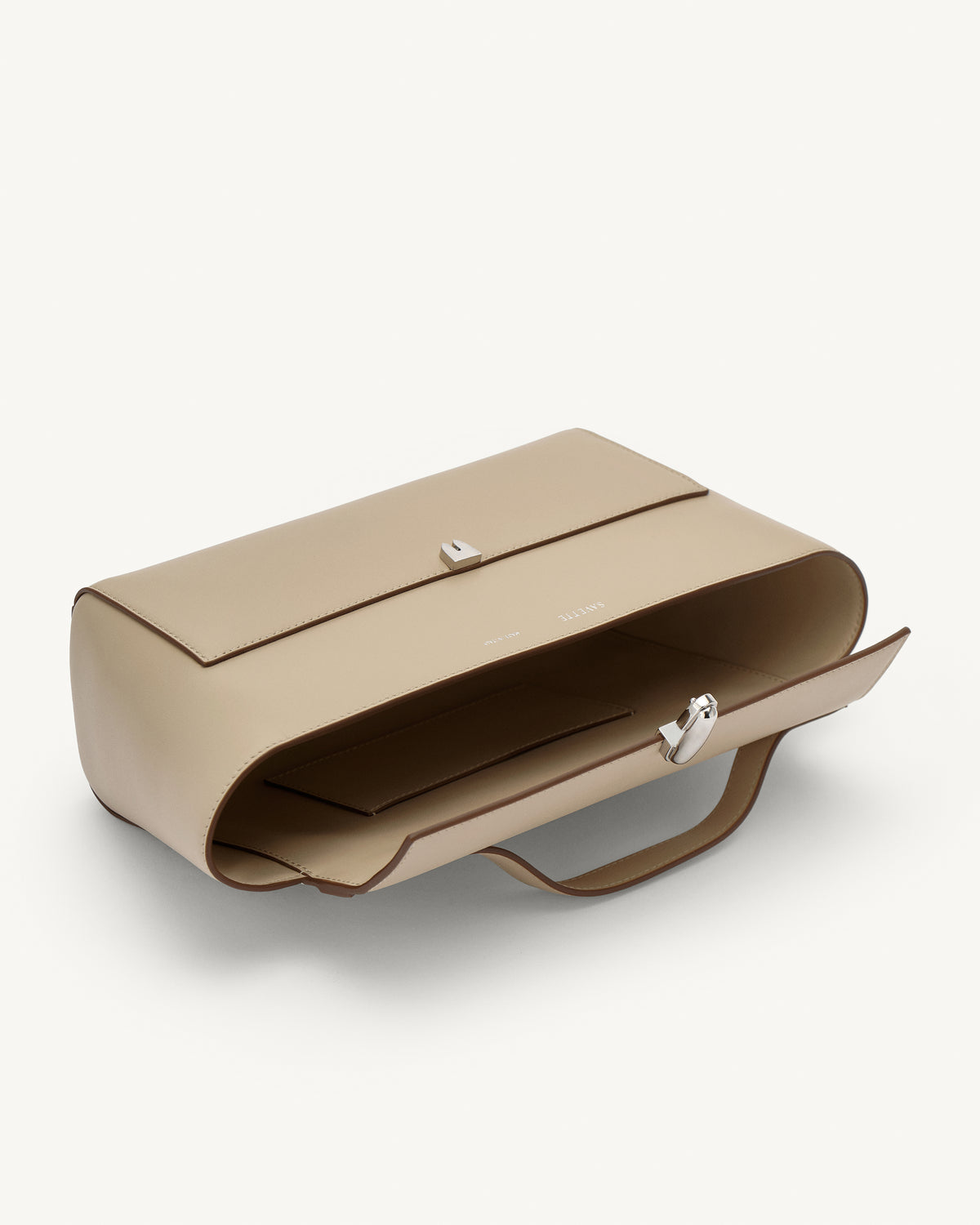 interior view of a bone beige leather bag with a silver clasp on a white background