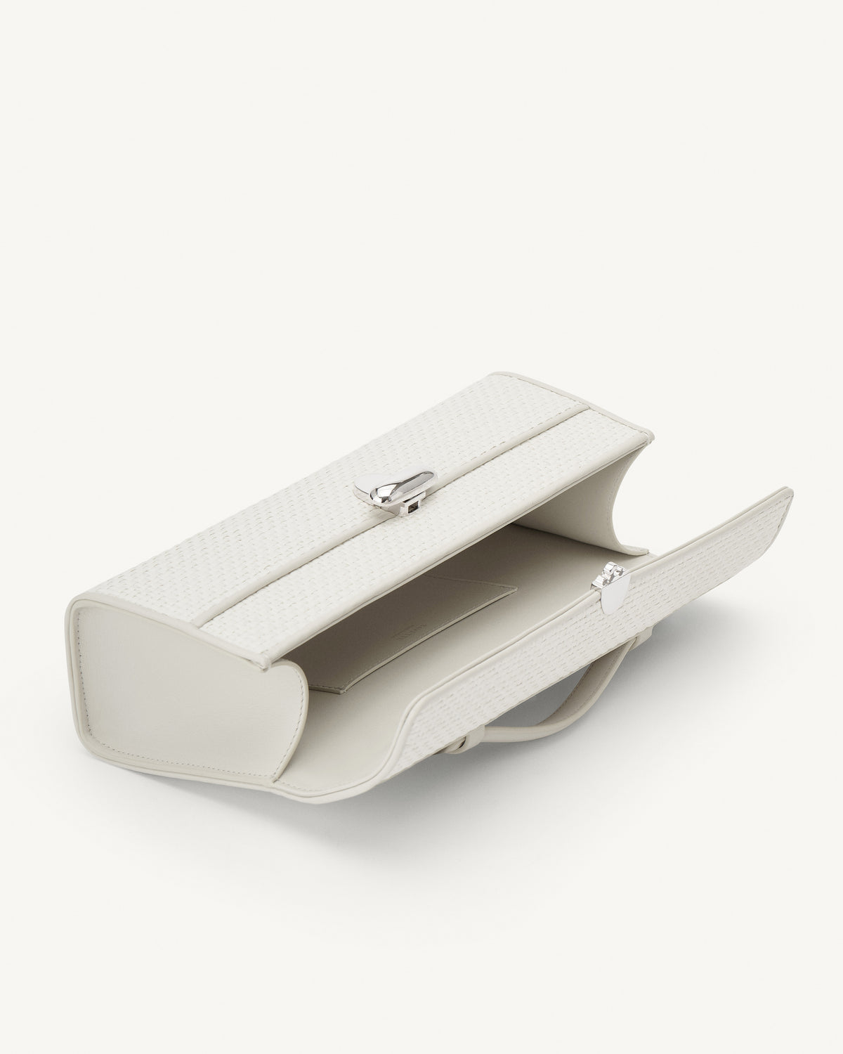 interior view of an ivory raffia bag with silver hardware on a white background