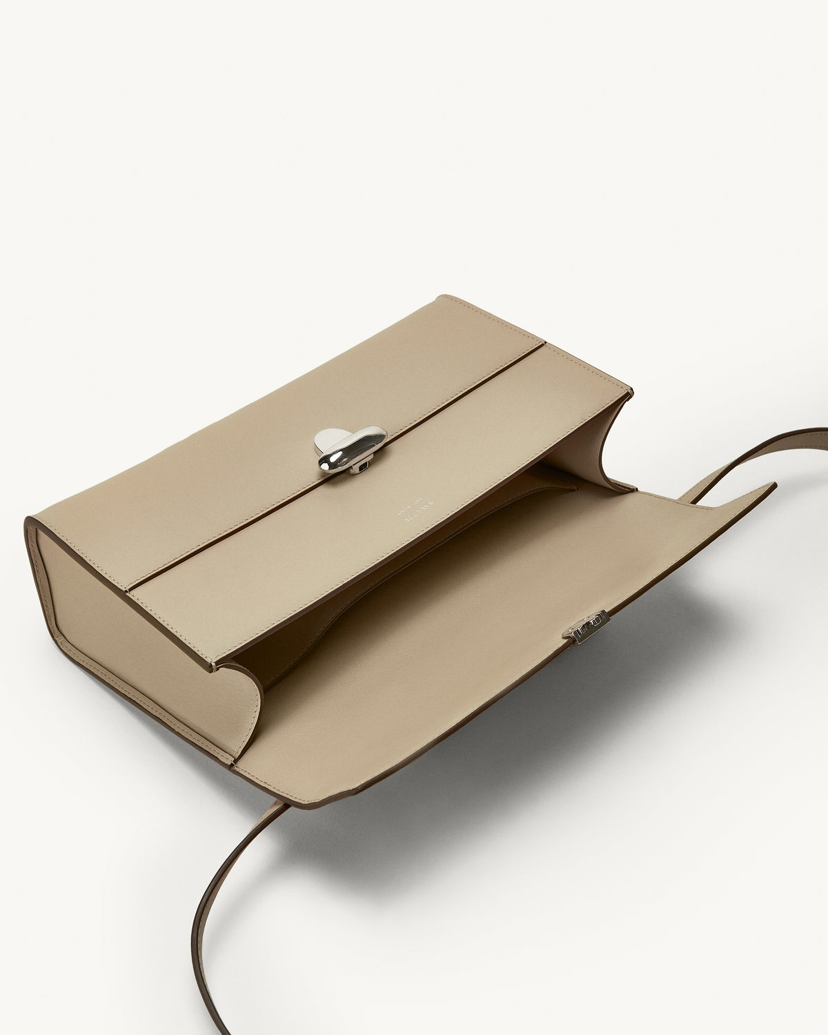 interior view of a bone beige leather bag with a silver clasp on a white background