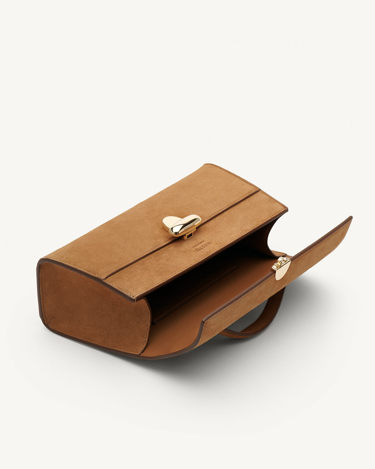 Inside view of Saddle Suede leather handbag with a gold clasp on a white background