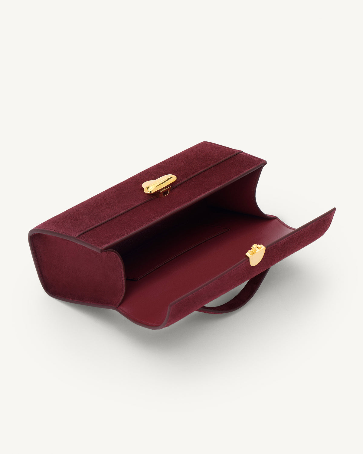 interior view of a plum red suede bag with gold clasp on a white background