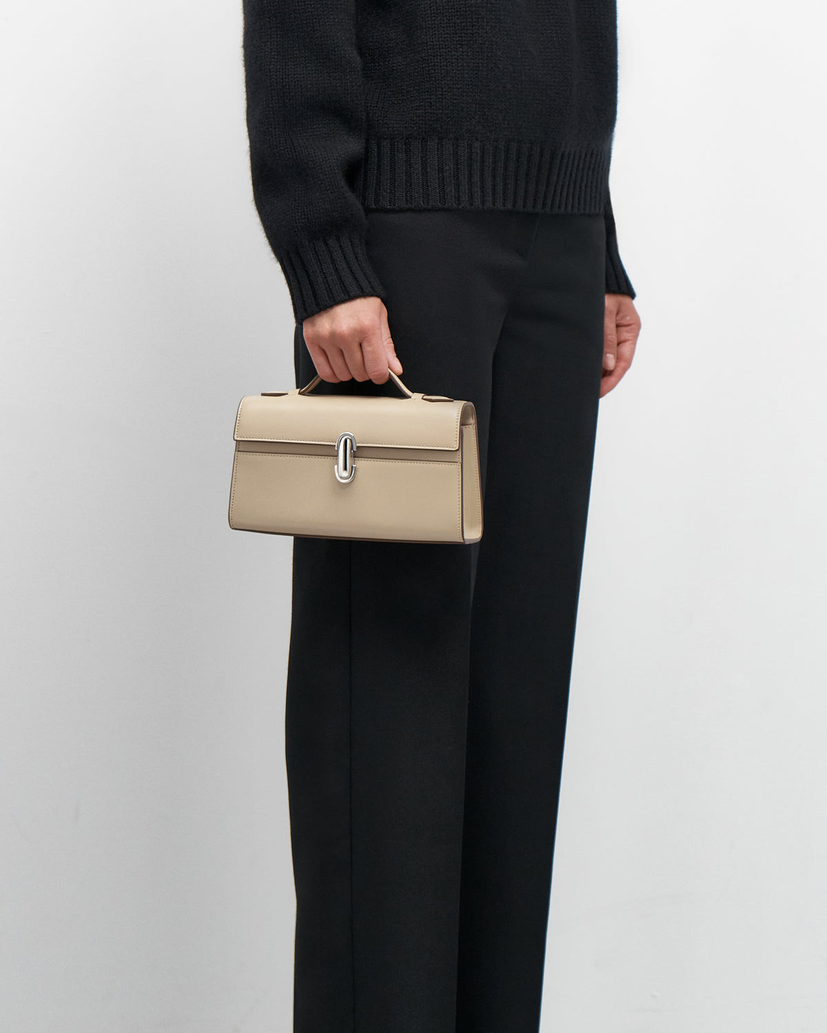 on model view of a bone beige leather bag with a silver clasp on a white background