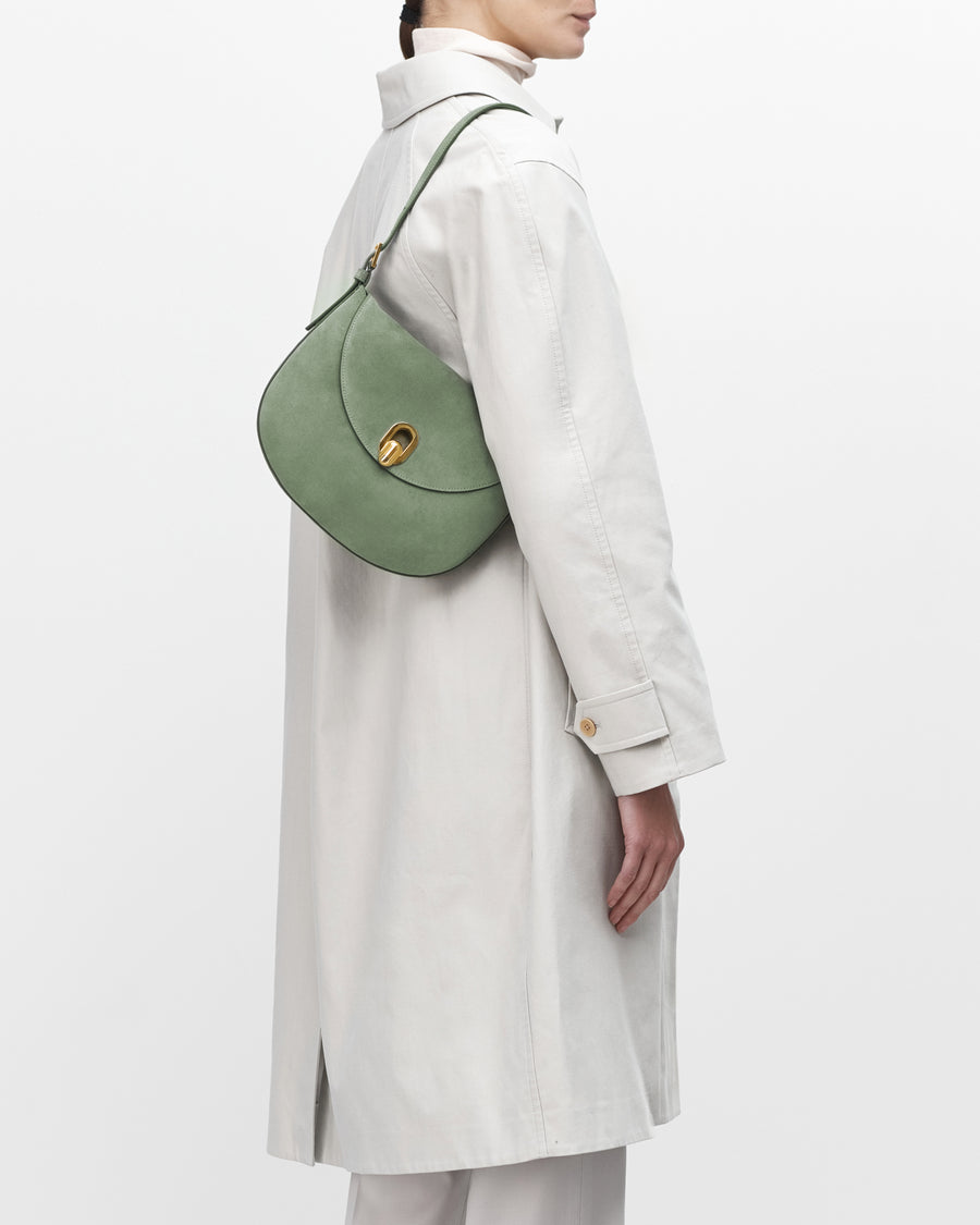 On model view cactus suede handbag with a gold clasp on a white background
