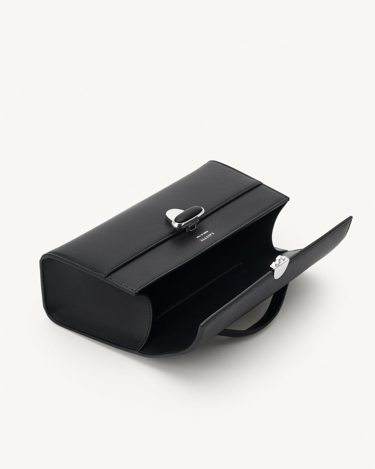 interior view of a black leather top handle bag with a black leather covered silver clasp on a white background