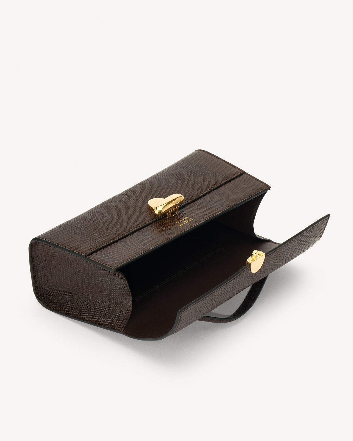 interior view of currant brown lizard bag with gold clasp on a white background