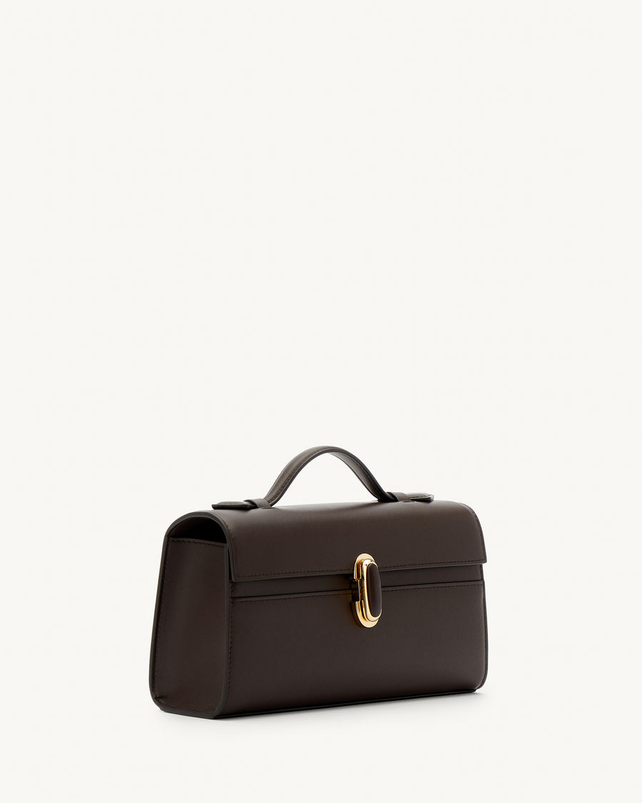 side view of a coffee brown leather top handle bag with a coffee brown leather covered gold clasp on a white background