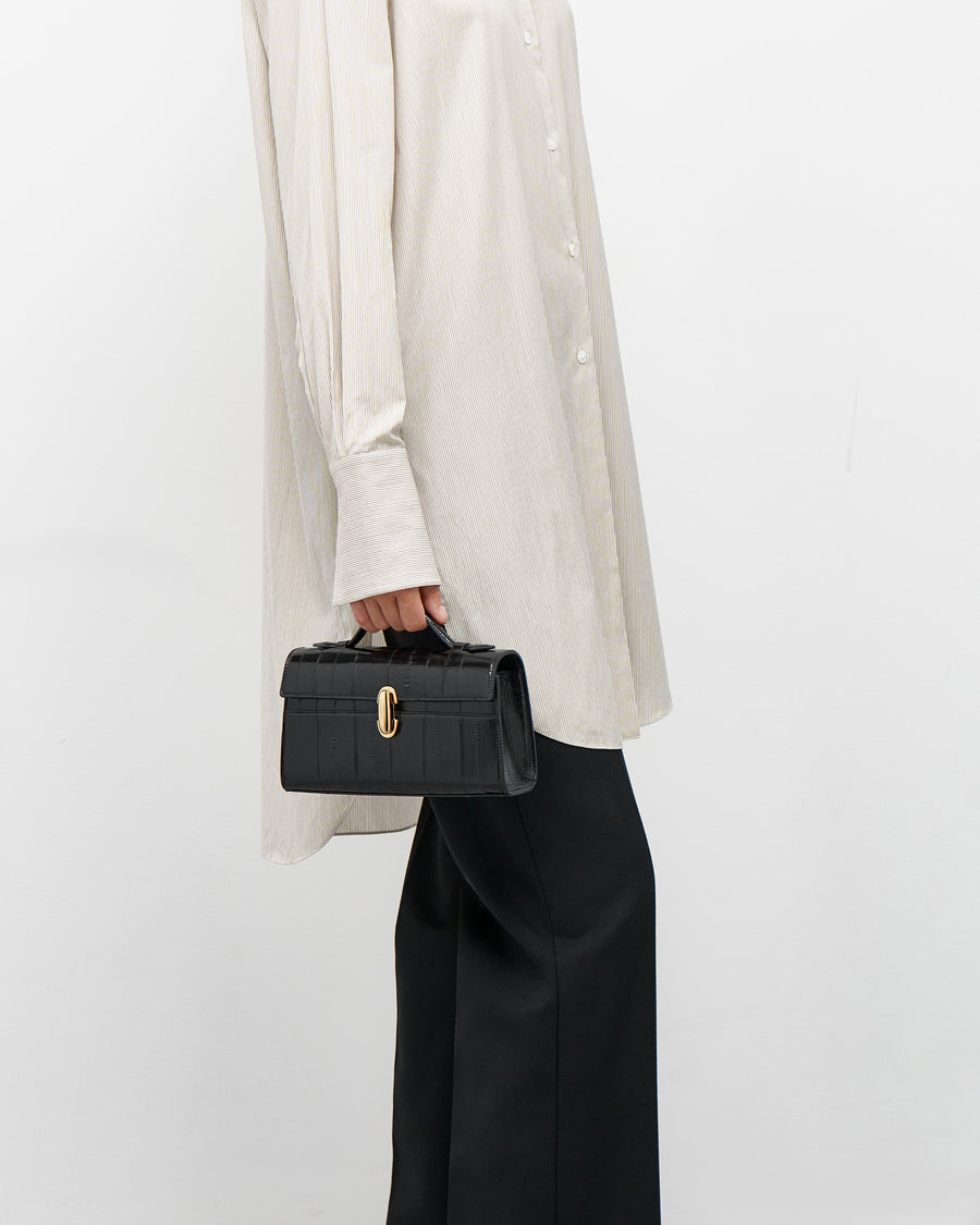 on model view of a black eel bag with a gold clasp on a white background