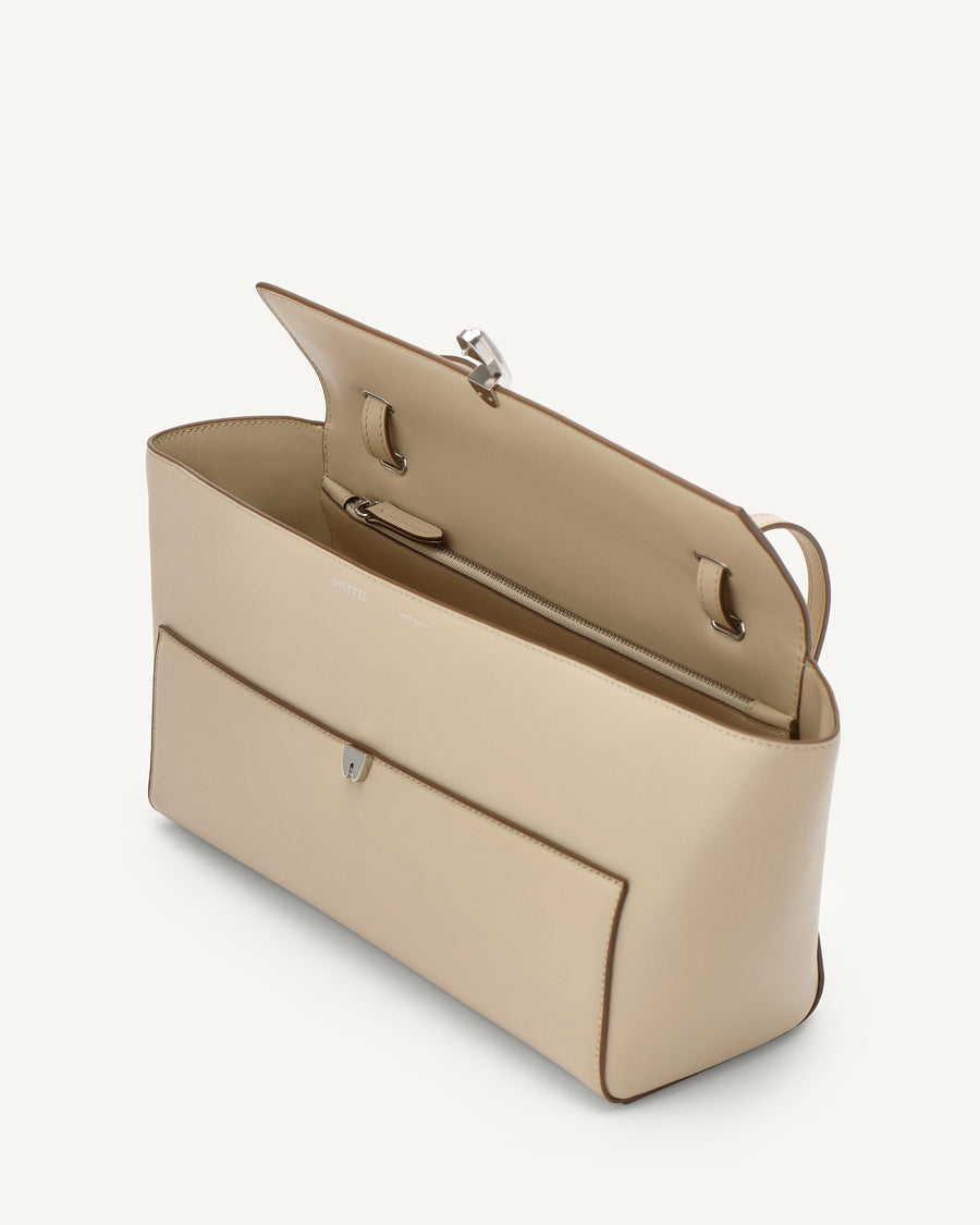 side view of a bone beige leather bag with a silver clasp on a white background