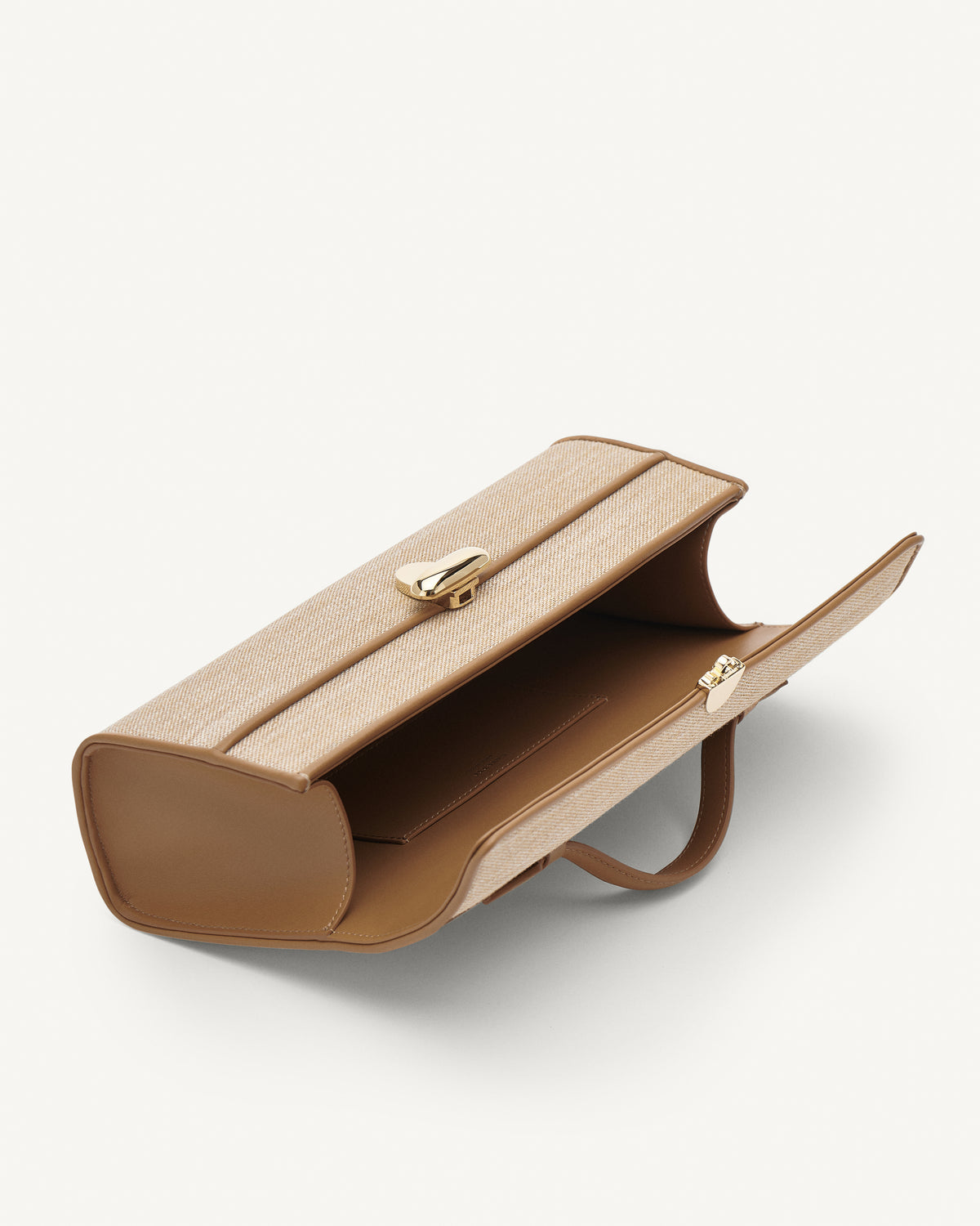 Inside view of canvas handbag with a gold clasp on a white background