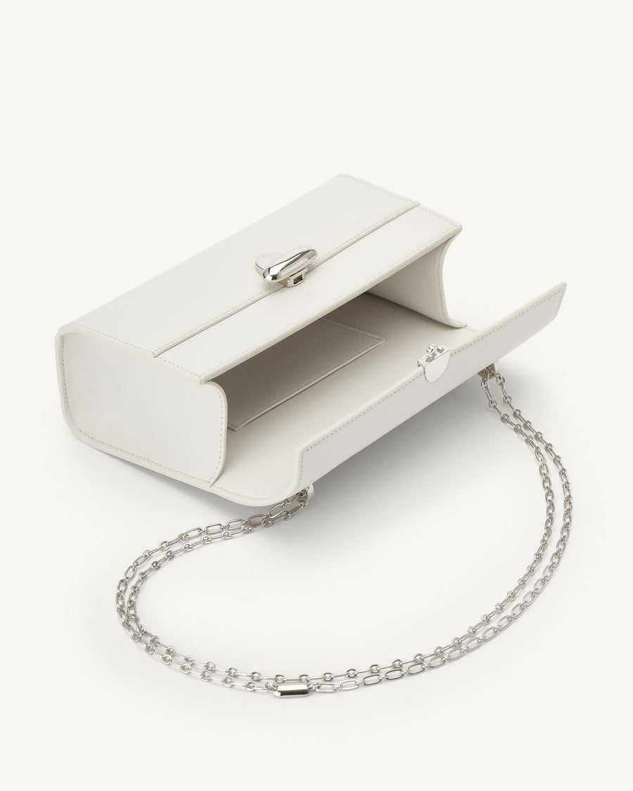 interior view of an ivory leather bag with silver clasp and silver chain on a white background