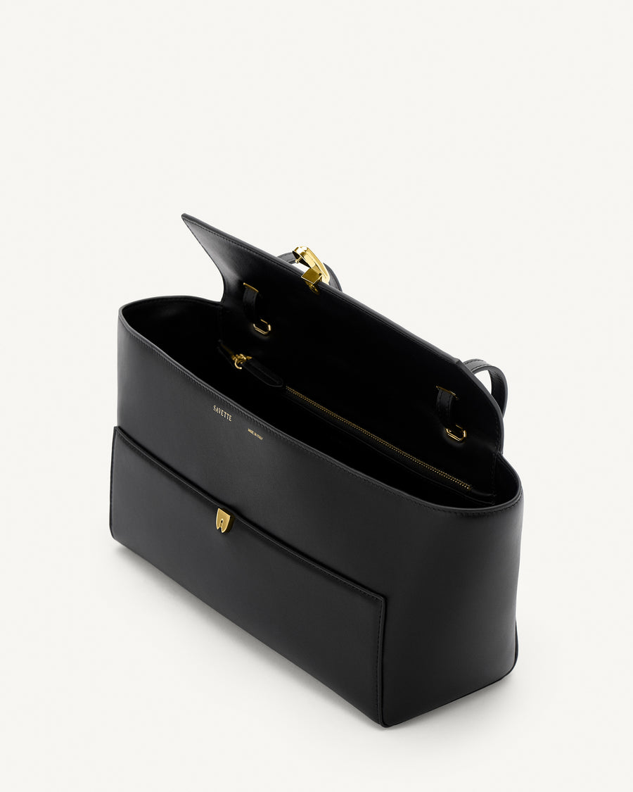 interior view of a black leather bag with a gold clasp on a white background 