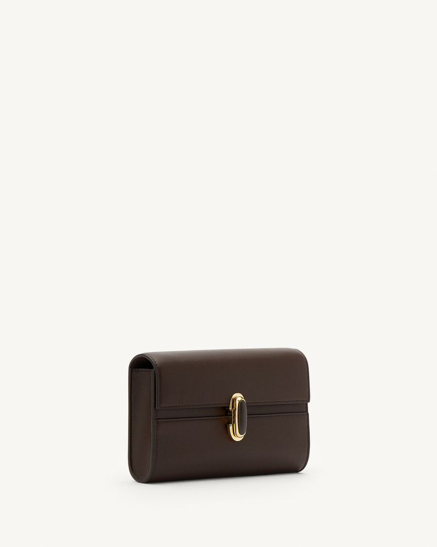 side view of a coffee brown leather bag with a coffee brown leather covered gold clasp on a white background