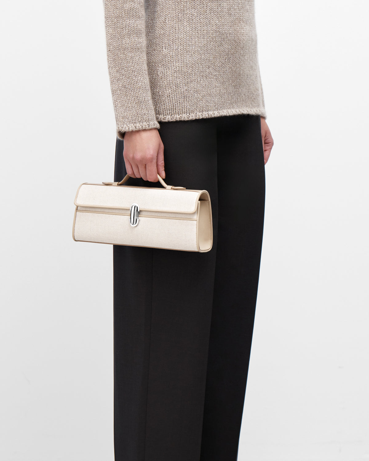 On Model view of Beige handbag with a silver clasp on a white background