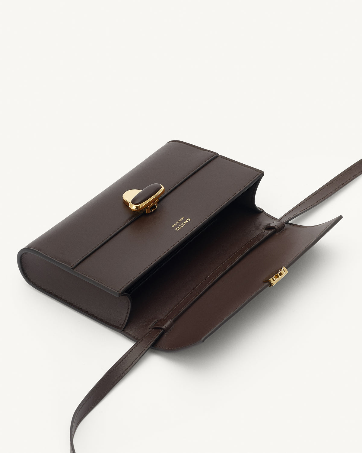 interior view of a coffee brown leather bag with a coffee brown leather covered gold clasp on a white background