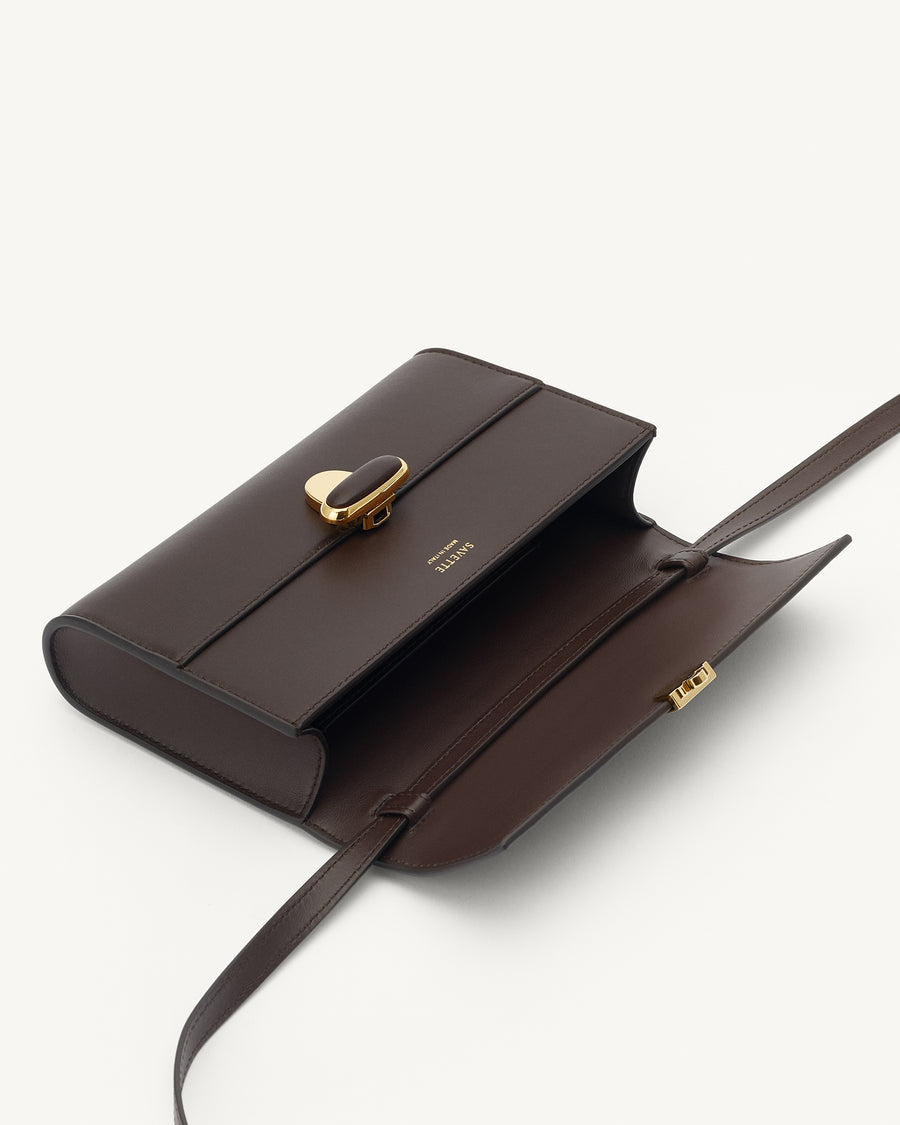 interior view of a coffee brown leather bag with a coffee brown leather covered gold clasp on a white background