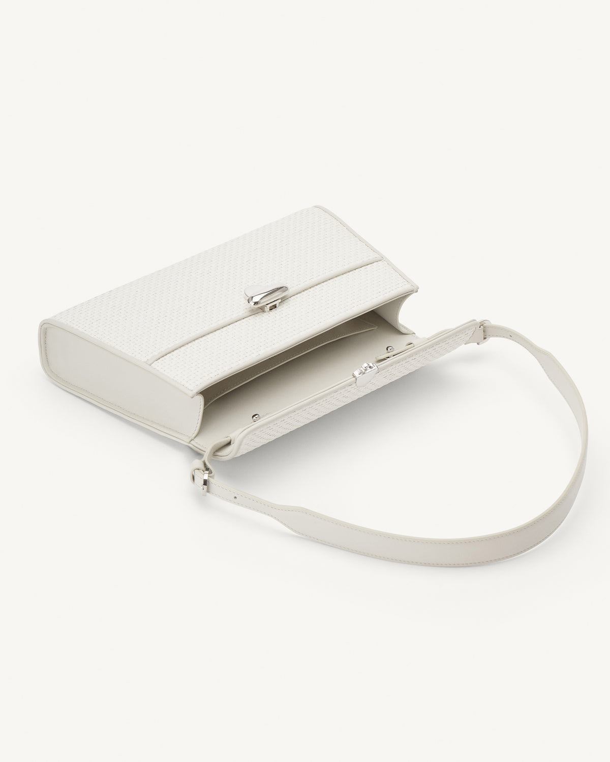 interior view of a white raffia bag with leather trim and silver clasp on a white background