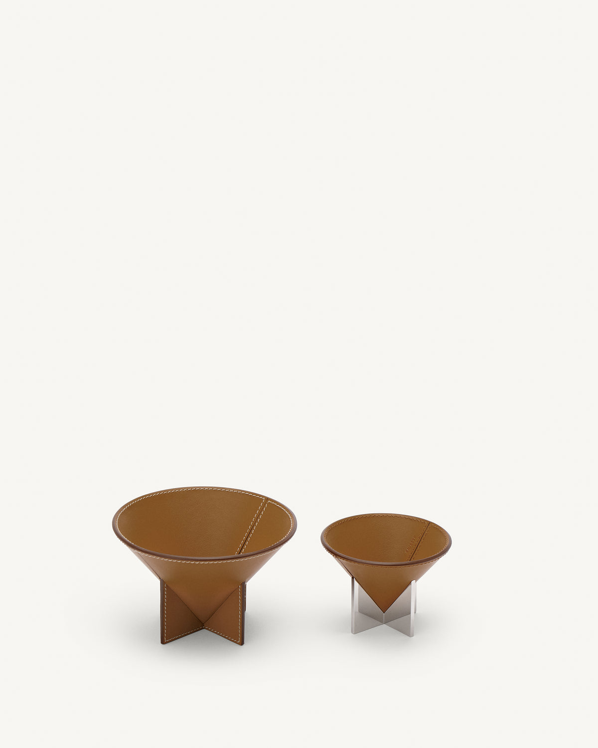 interior view of two saddle brown leather dishes, one with silver metal feet, on a white background