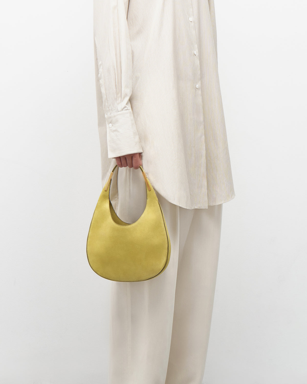 on model view of a chartreuse green suede bag with gold hardware on a white background
