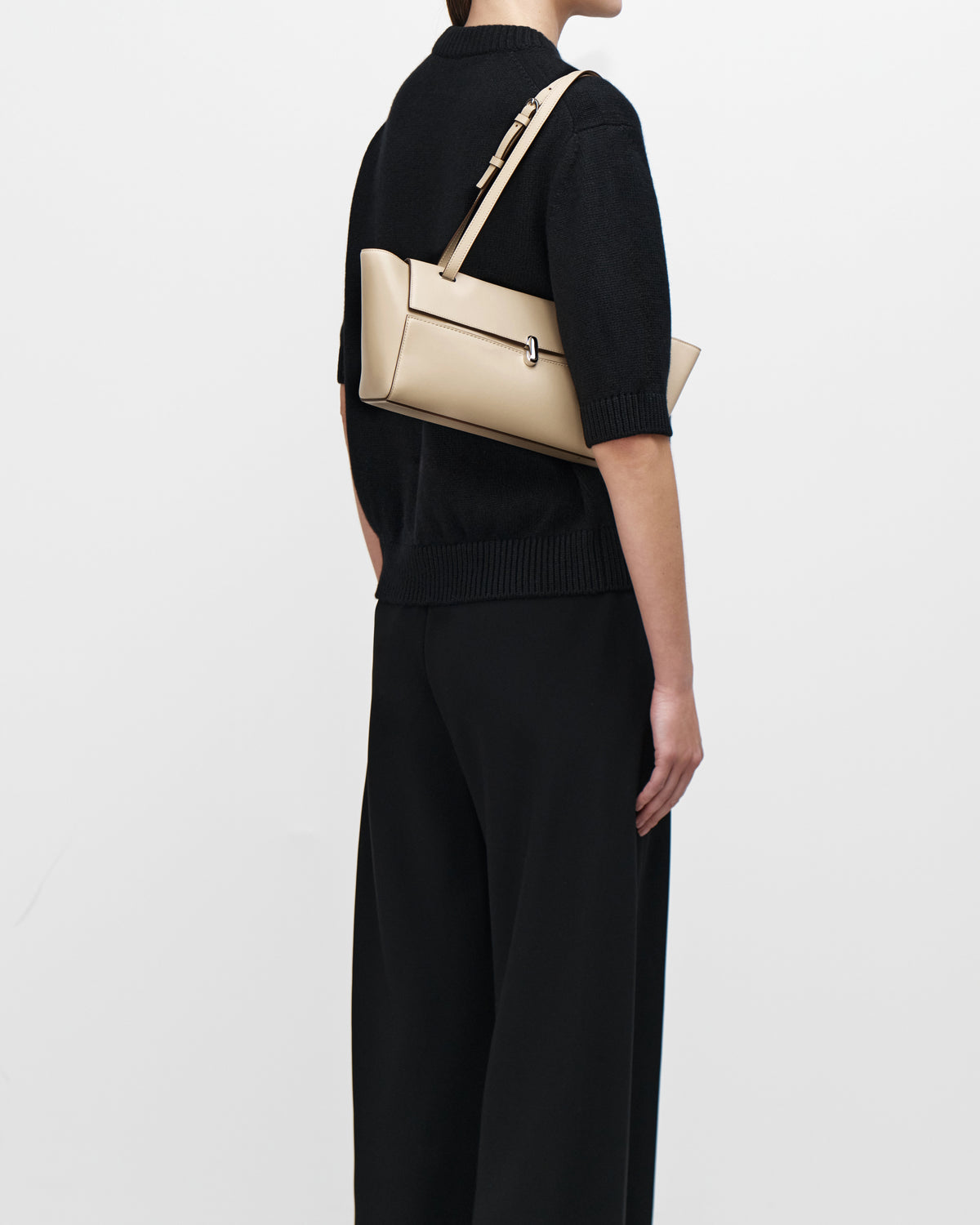 on model image of a bone beige leather bag with a silver clasp on a white background
