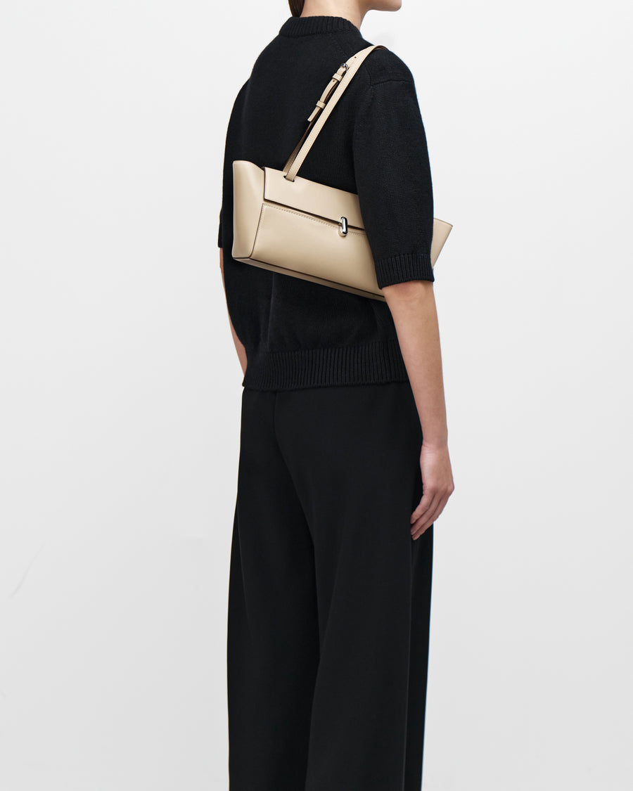 on model image of a bone beige leather bag with a silver clasp on a white background