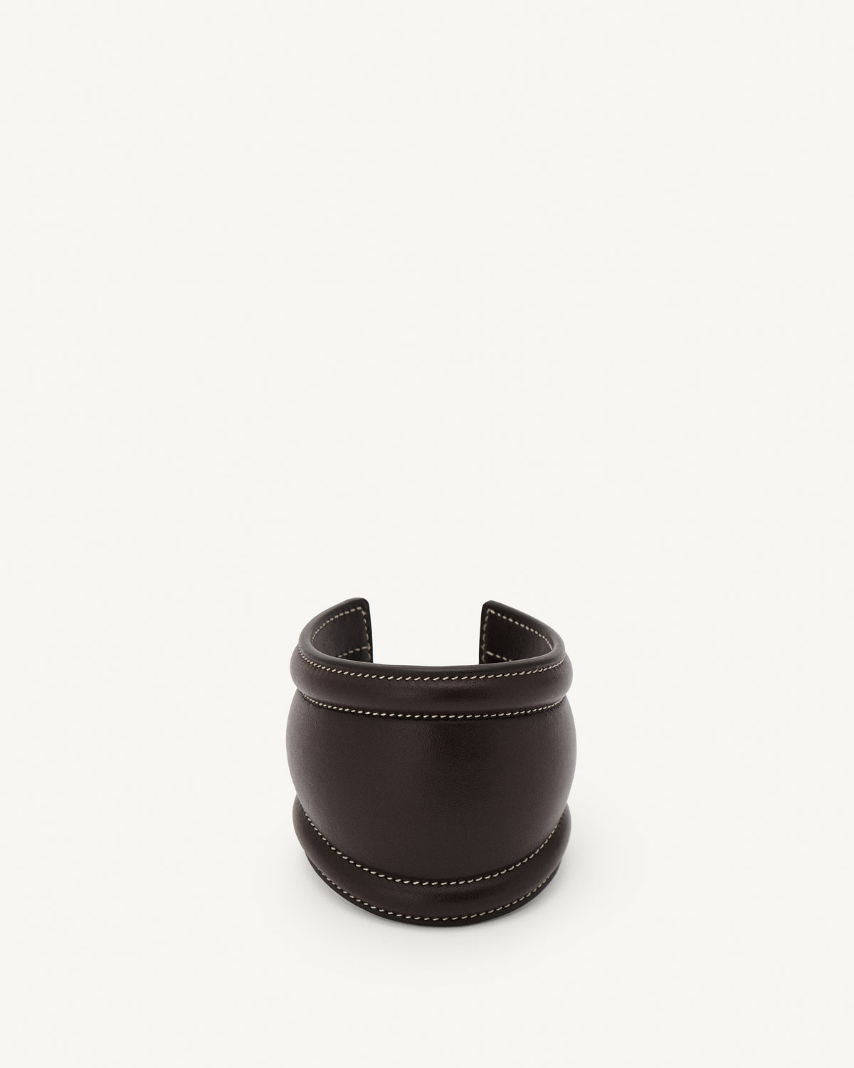 front view of a coffee brown leather cuff with white stitching on a white background 