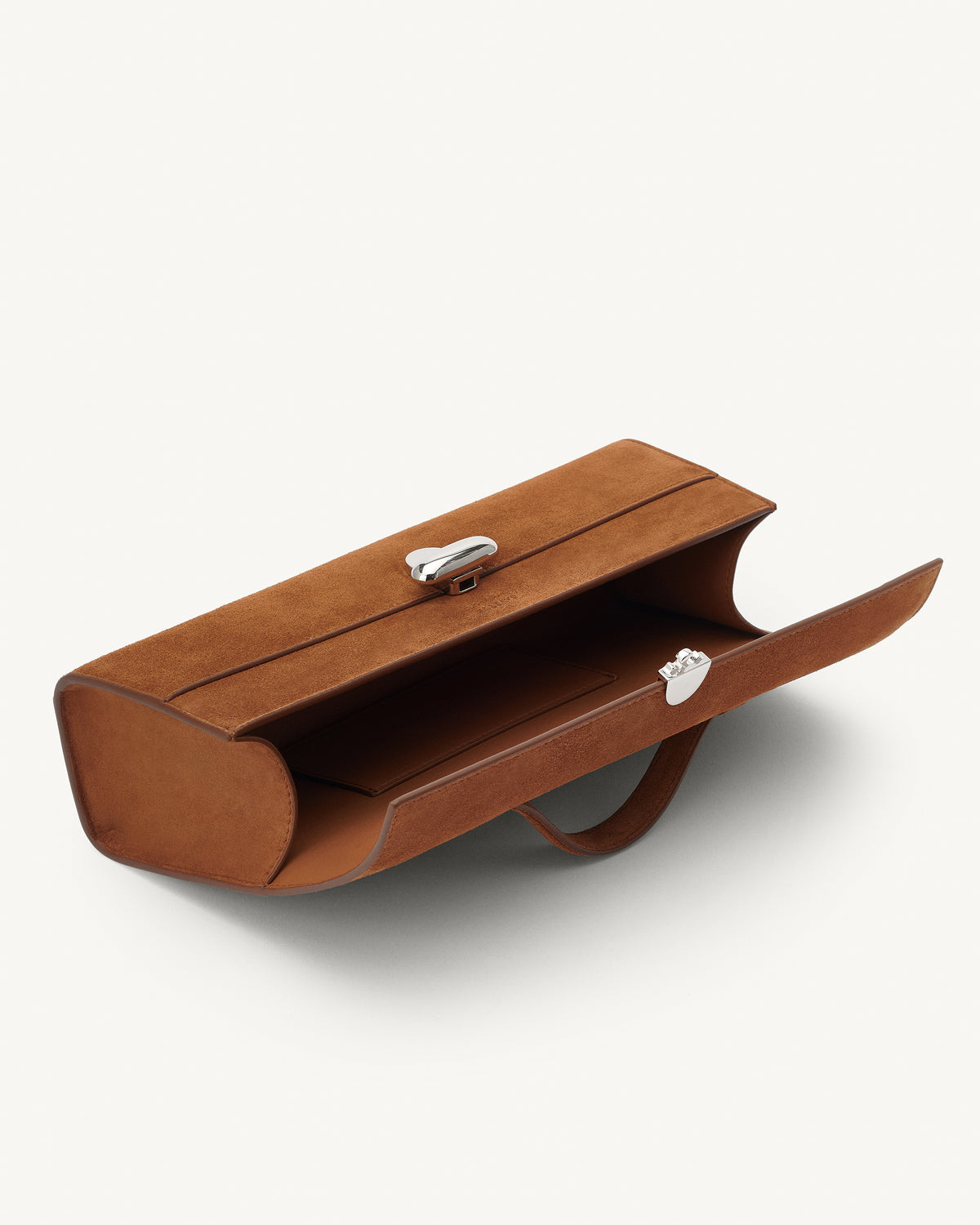 interior view of a cognac brown suede top handle bag with a silver clasp on a white background 