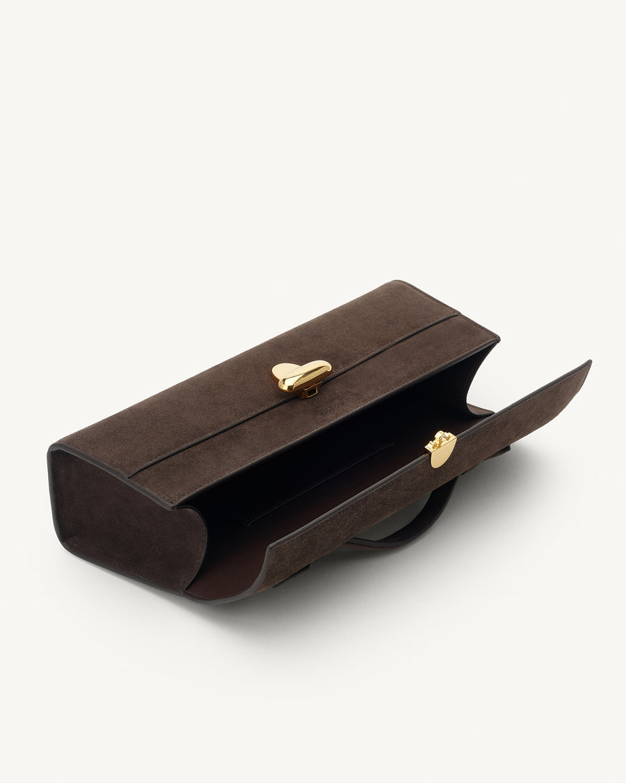 interior view of a coffee brown suede top handle bag with a gold clasp on a white background 