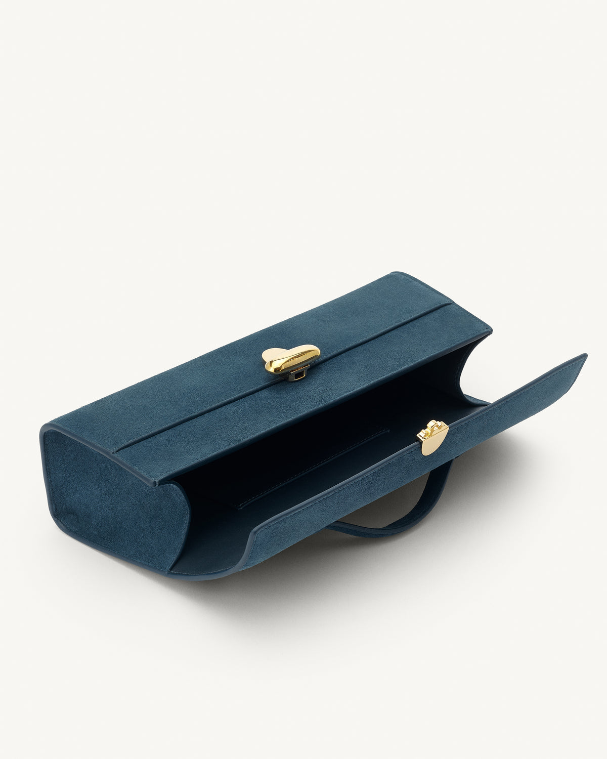 interior view of a baltic blue suede top handle bag with a gold clasp on a white background 