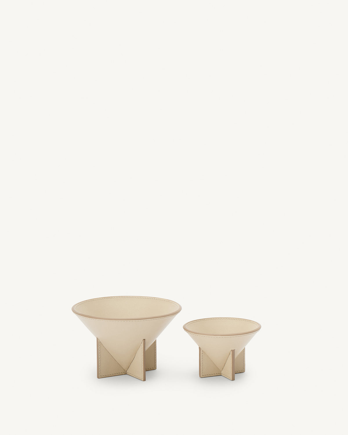 front view of two parchment beige leather dishes on a white background