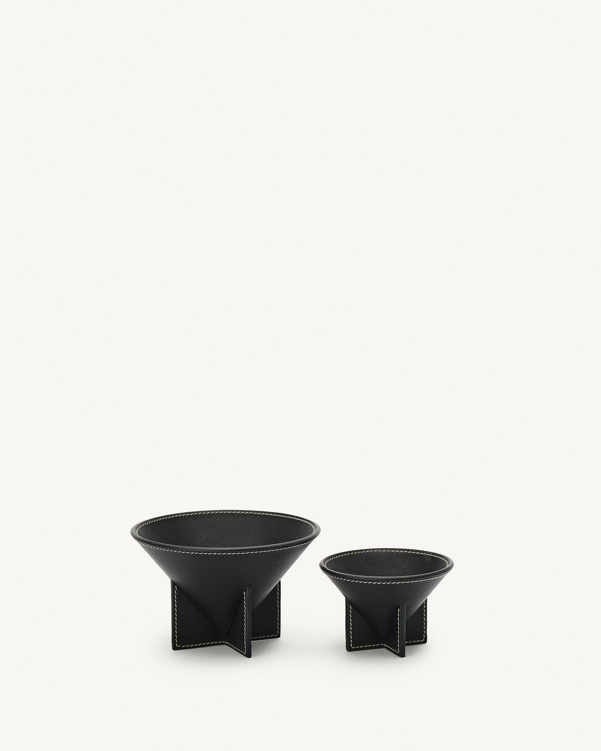 front view of two ebony black leather dishes on a white background