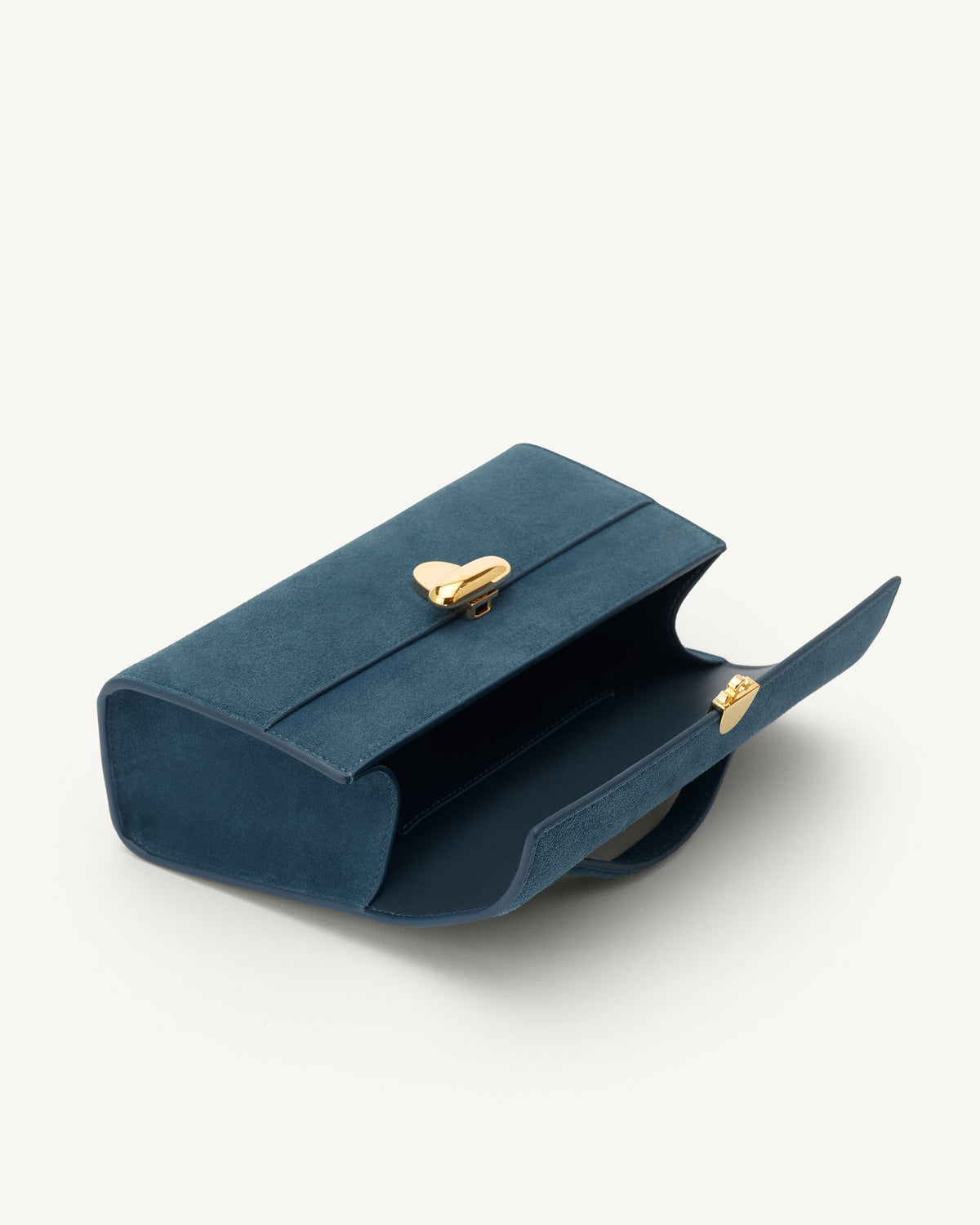 interior view of a baltic blue suede top handle bag with a gold clasp on a white background 