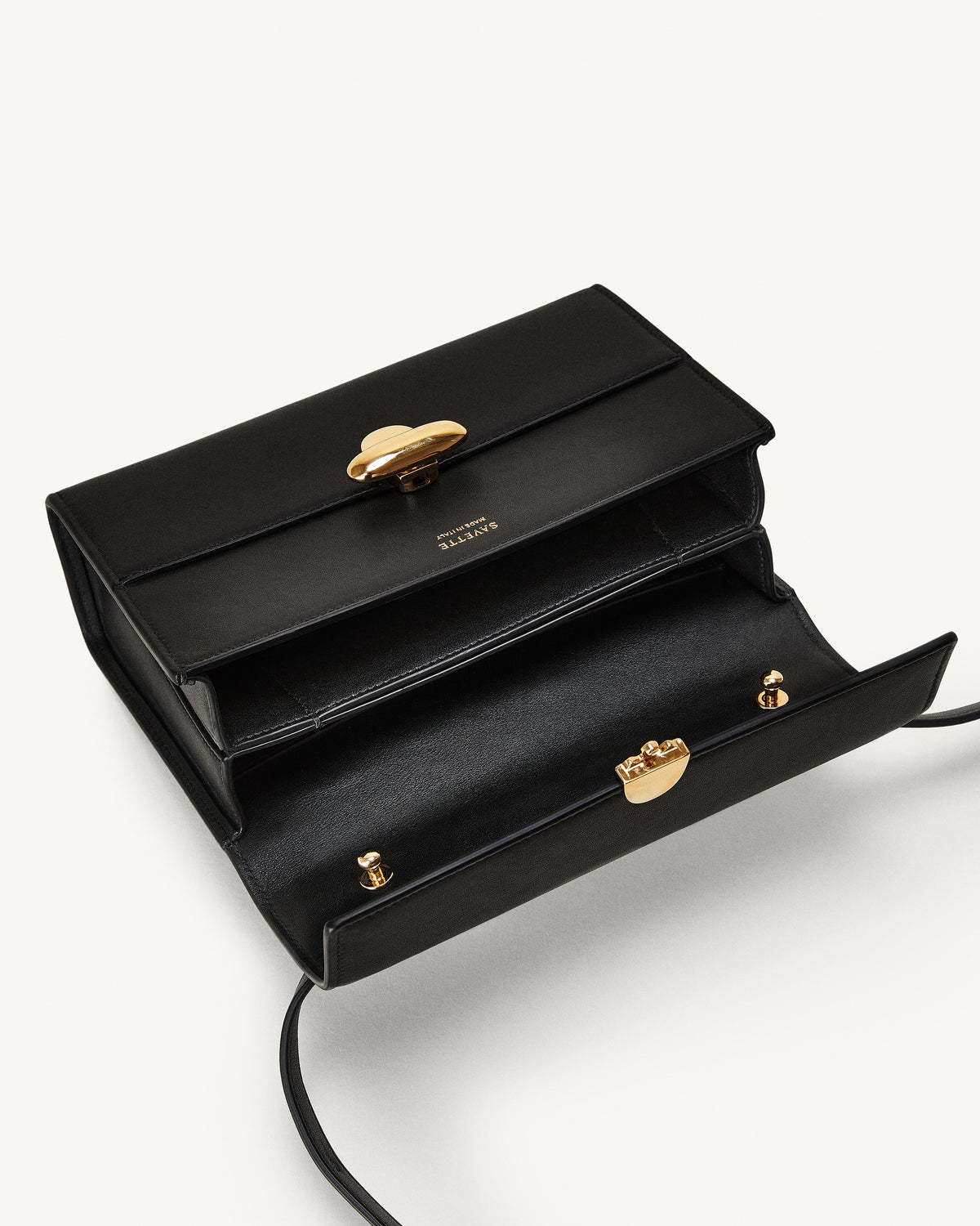 interior view of a black leather bag with a gold clasp on a white background