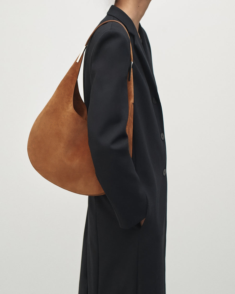 on-model view of a cognac brown suede shoulder bag with silver hardware 
