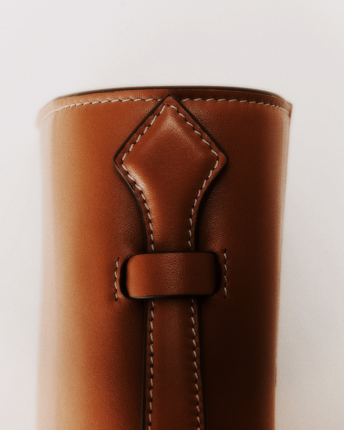 Editorial aerial view of the top handle of a maple brown bag with white stitching