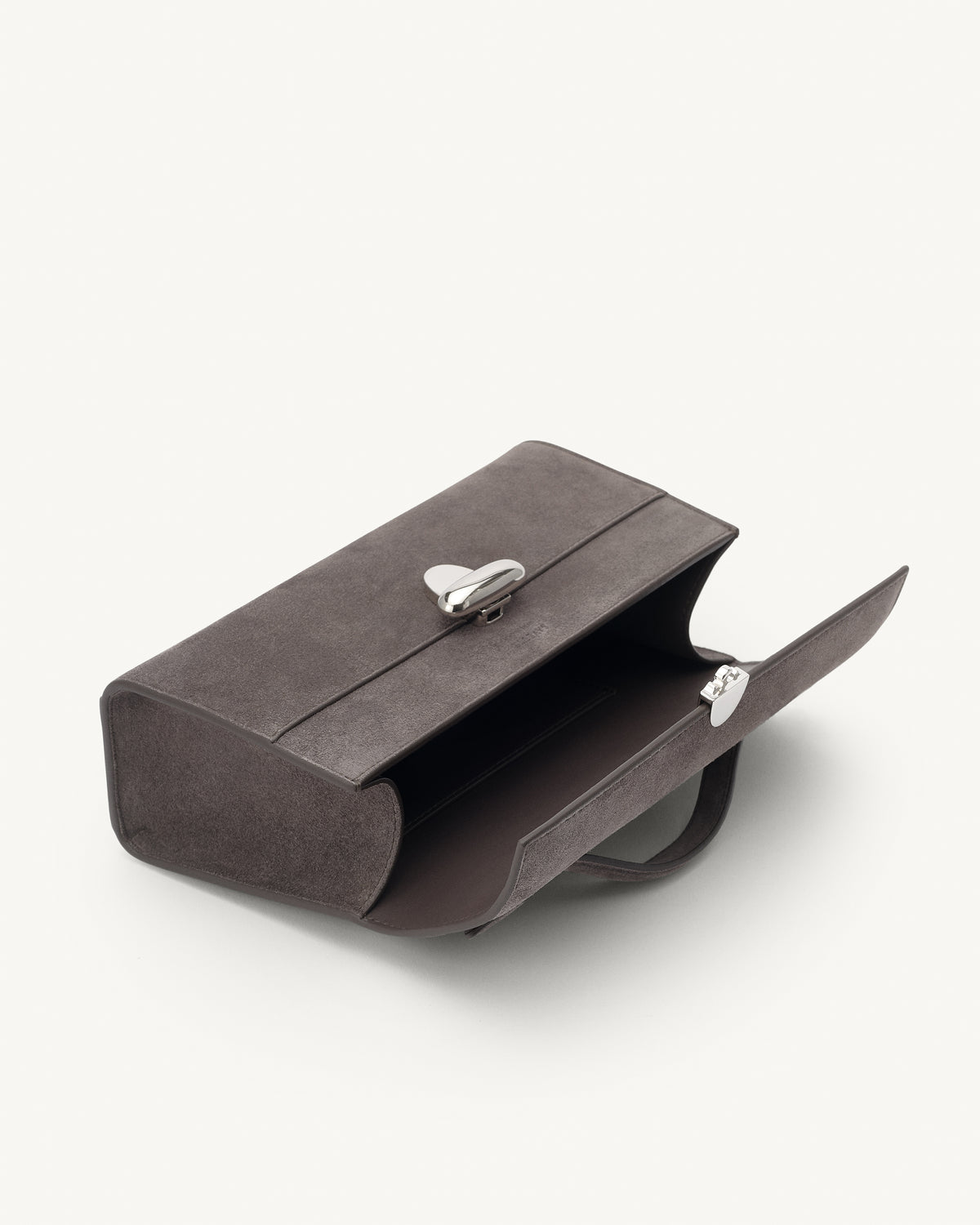 interior view of a smoke grey suede top handle bag with a silver clasp on a white background