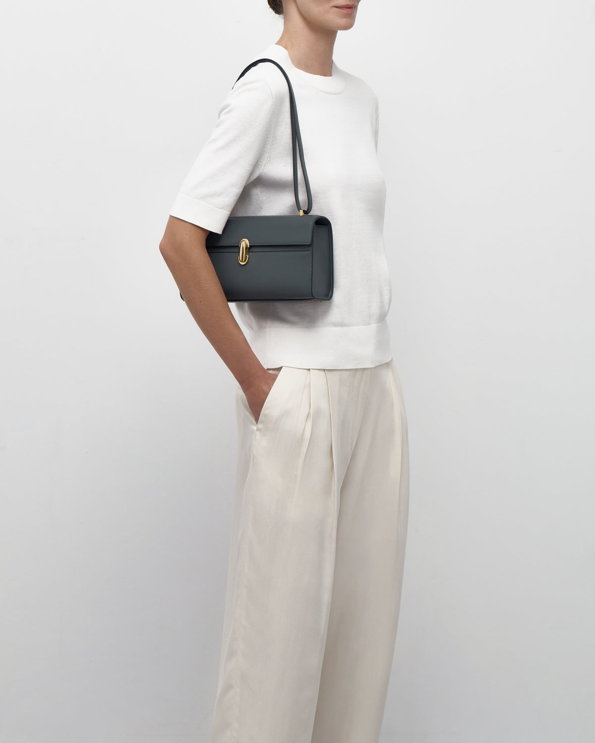 on model view of a storm blue leather bag with a gold clasp on a white background
