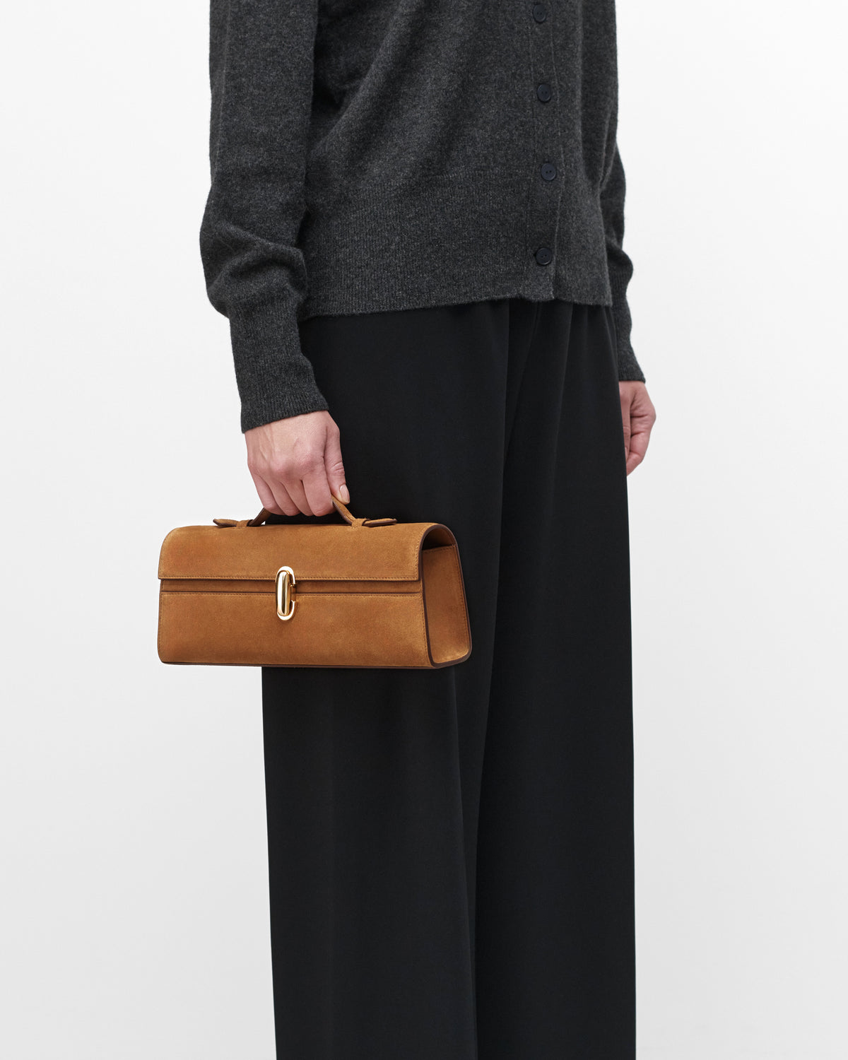 On model view of Saddle Suede leather handbag with a silver clasp on a white background