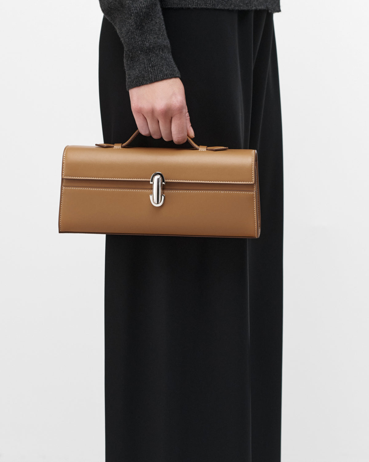 On model view of Saddle leather handbag with a silver clasp on a white background