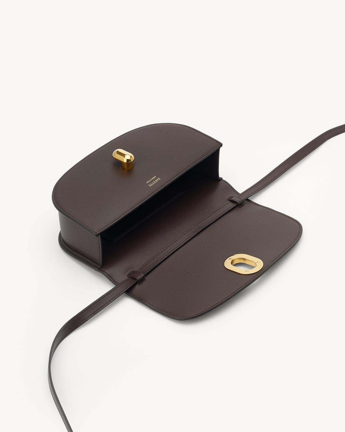 interior view of a coffee brown leather handbag with gold hardware on a white background