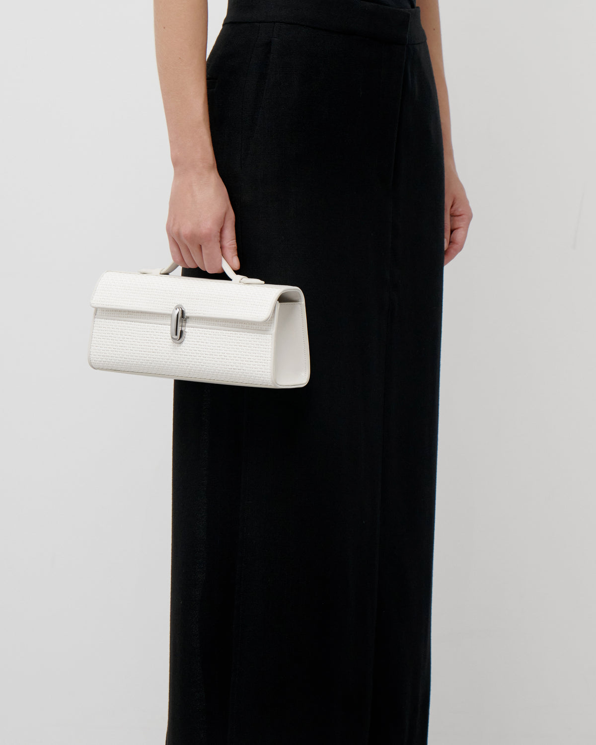 on model view of an ivory raffia bag with a silver clasp on a white background