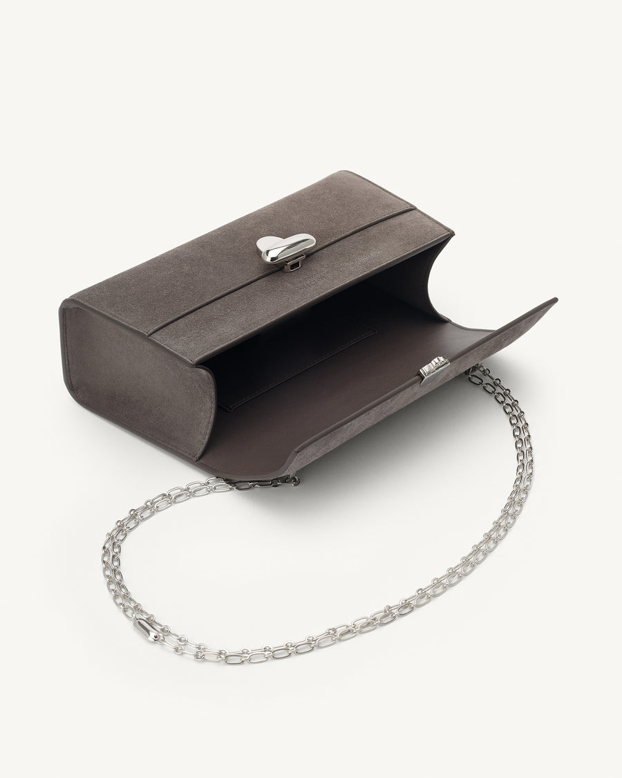 interior view of a smoke grey suede bag with a silver chain and silver clasp on a white background 