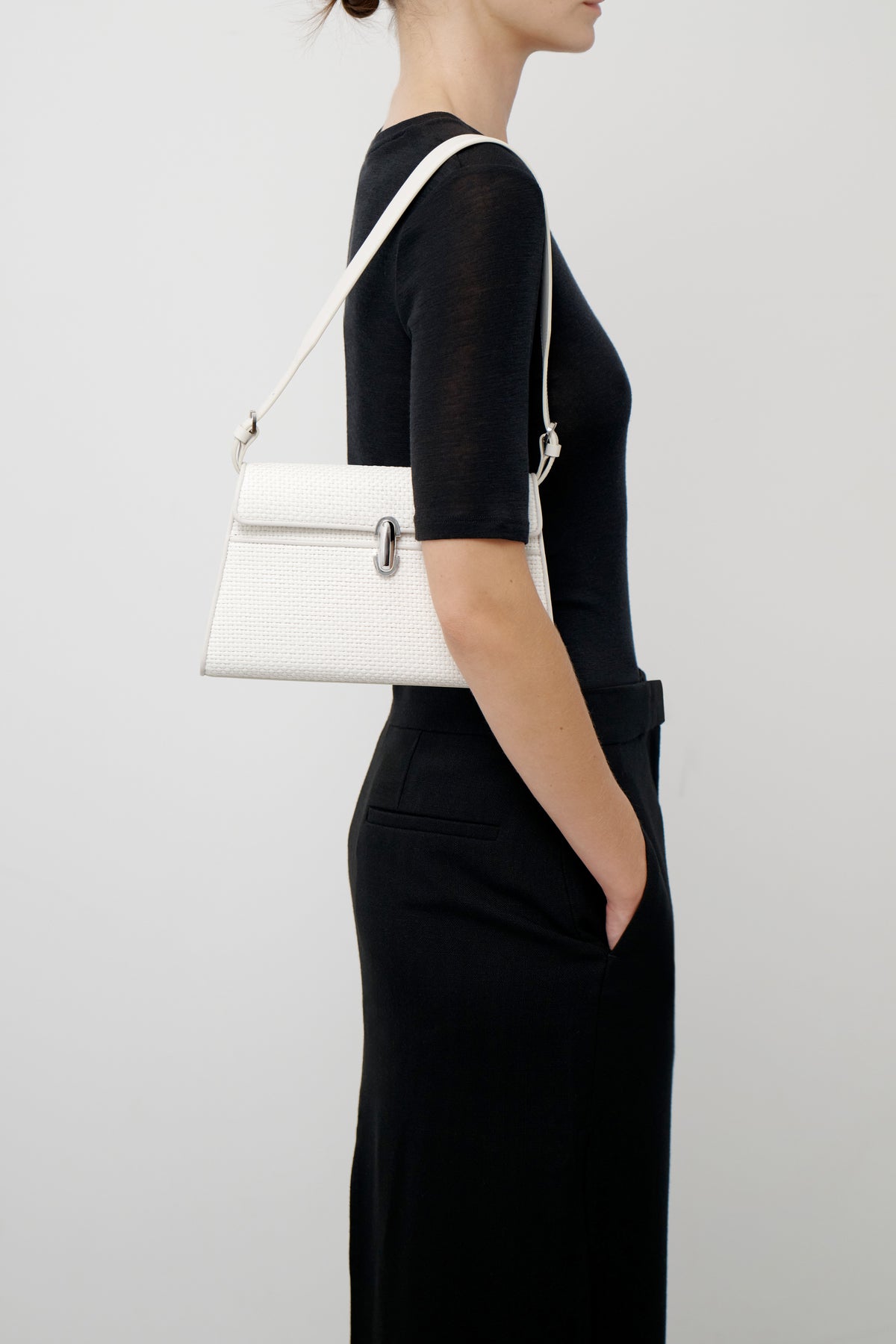 on model view of an ivory leather bag with silver clasp and chain on a white background