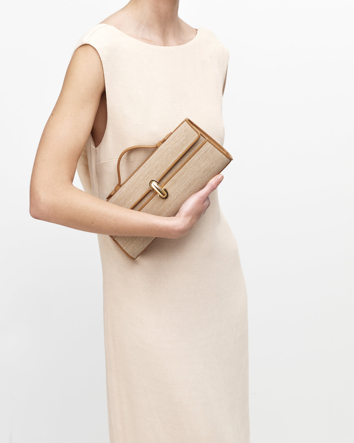 On model view of canvas handbag with a gold clasp on a white background
