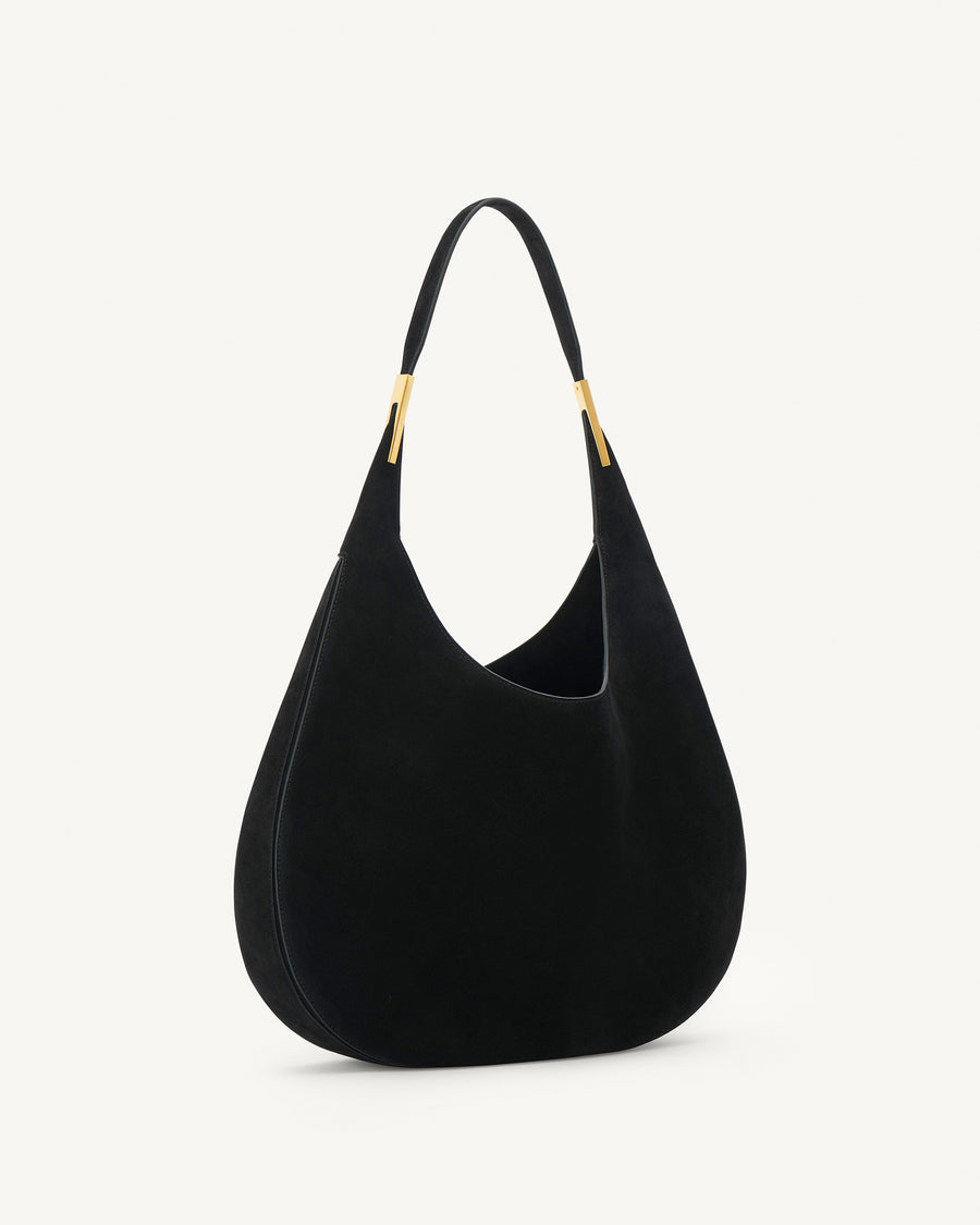 side view of black suede bag with gold hardware on a white background