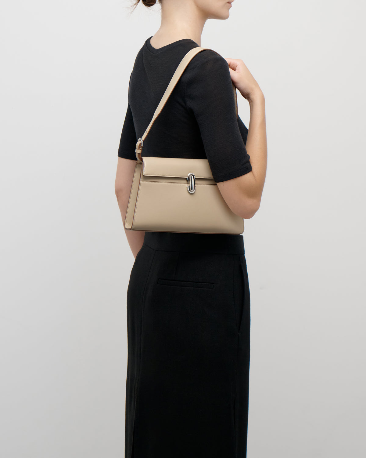 on model view of a bone beige leather bag with silver clasp on a white background