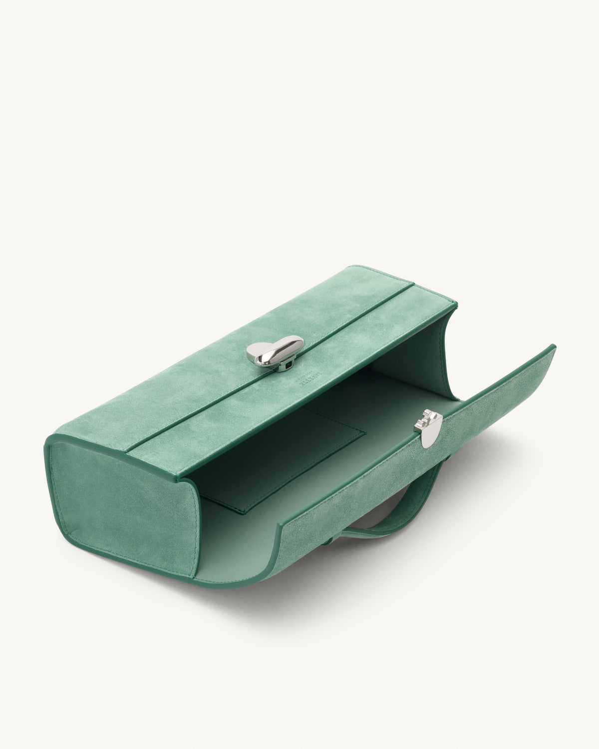 interior view of jade green suede bag with silver clasp on a white background